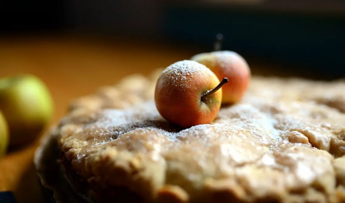 a pie with two small apples sitting on top